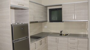 Una cocina moderna con armarios de madera clara, electrodomésticos de acero inoxidable y una ventana integrada sobre el fregadero.