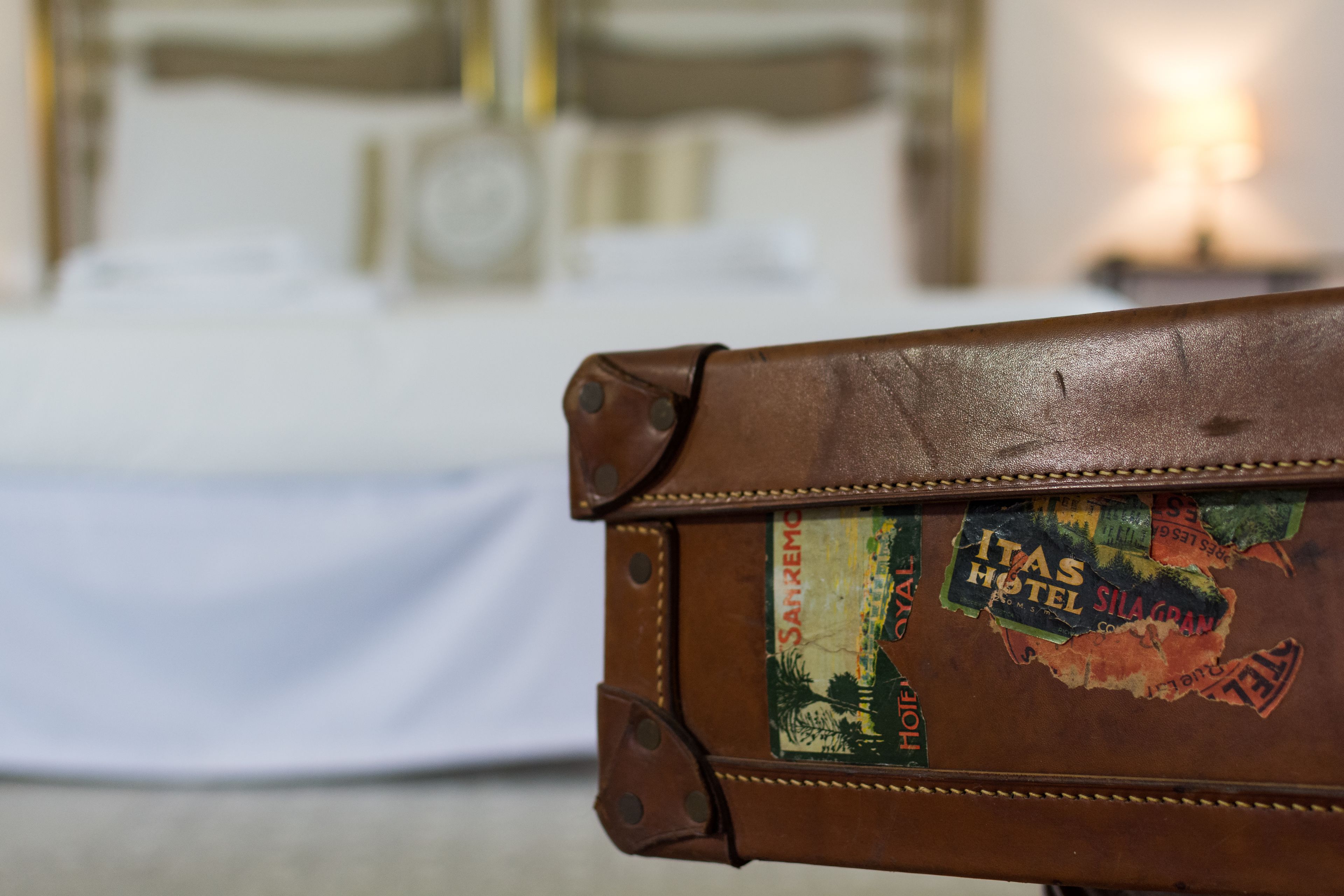 A brown leather suitcase with a vintage sticker that reads "ITAS HOTEL SILA GRAN."