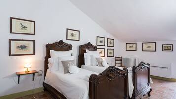Ein Schlafzimmer mit zwei Holzbett, weißer Bettwäsche und mehreren gerahmten Bildern an den Wänden.