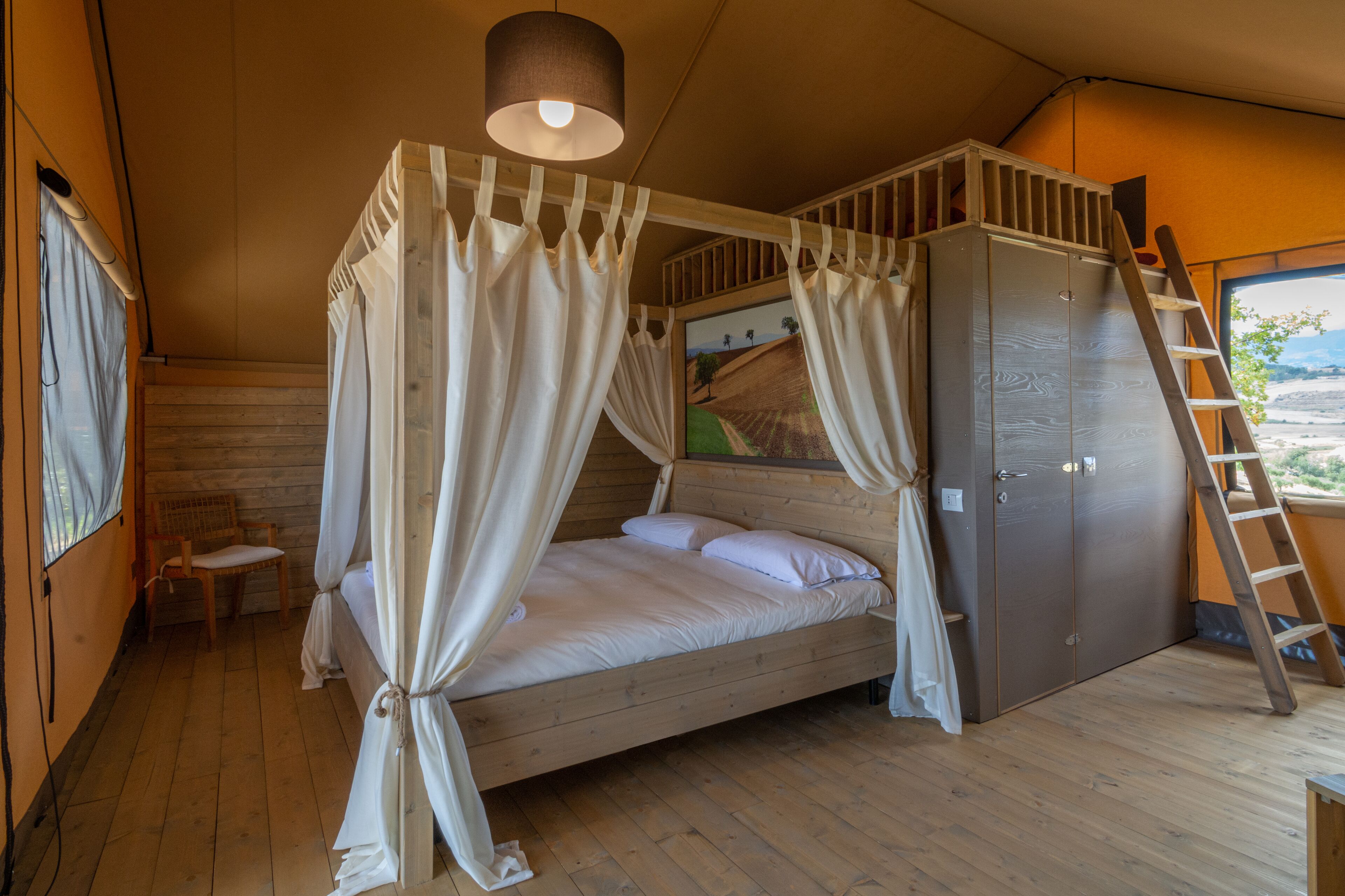 Ein Schlafzimmer in einer Holzhütte mit einem Bett, einem Kleiderschrank, einem Stuhl und einer Leiter.