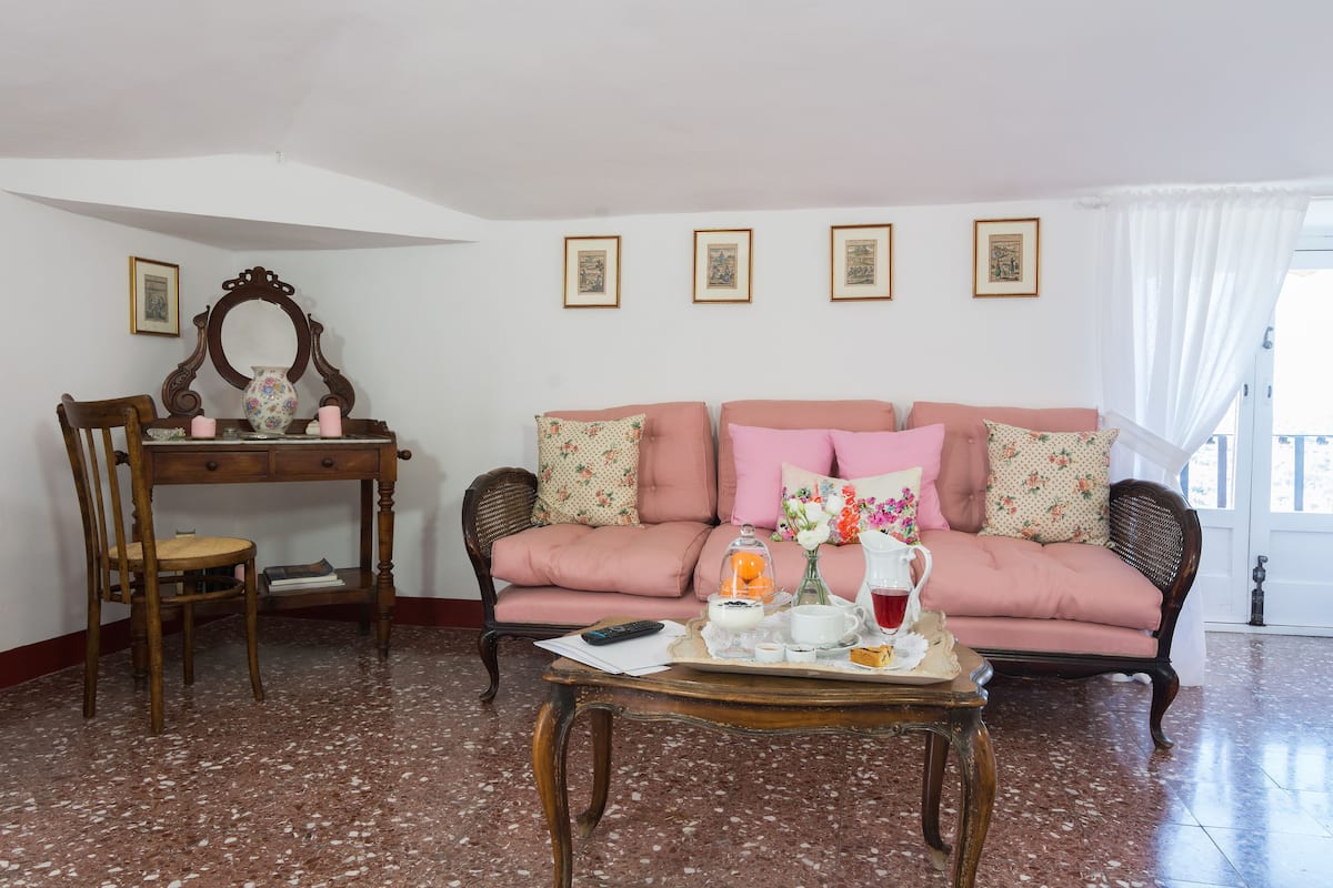 A room with a wooden desk, a pink sofa, and a coffee table with a tray of items.