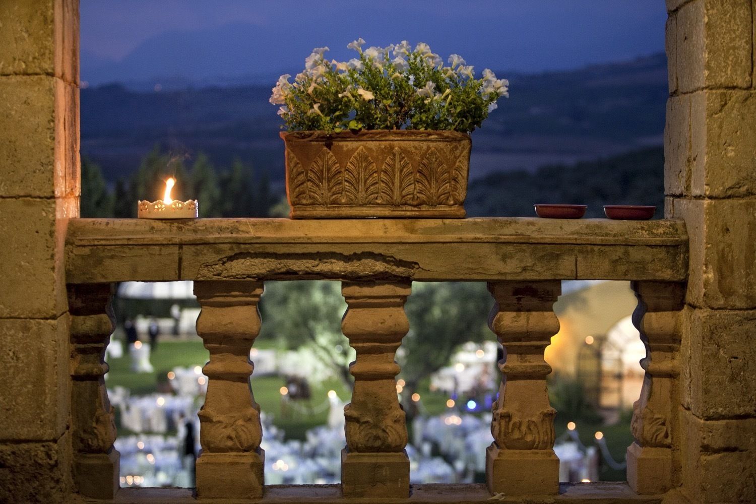 A stone balustrade with a potted plant and candles.