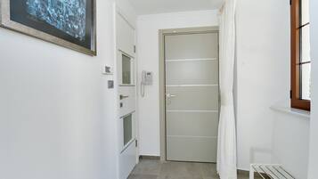 Un pasillo estrecho con una puerta, un teléfono y un pequeño banco.