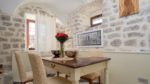 A dining area with a stone wall, a wooden table, and chairs. - Zebra  (Tivat)