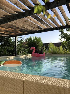Una piscina al aire libre de temporada, sillones reclinables de piscina