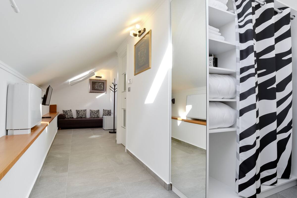 A modern, well-lit hallway with a sofa, a zebra-patterned shower curtain, and a framed picture on the wall.