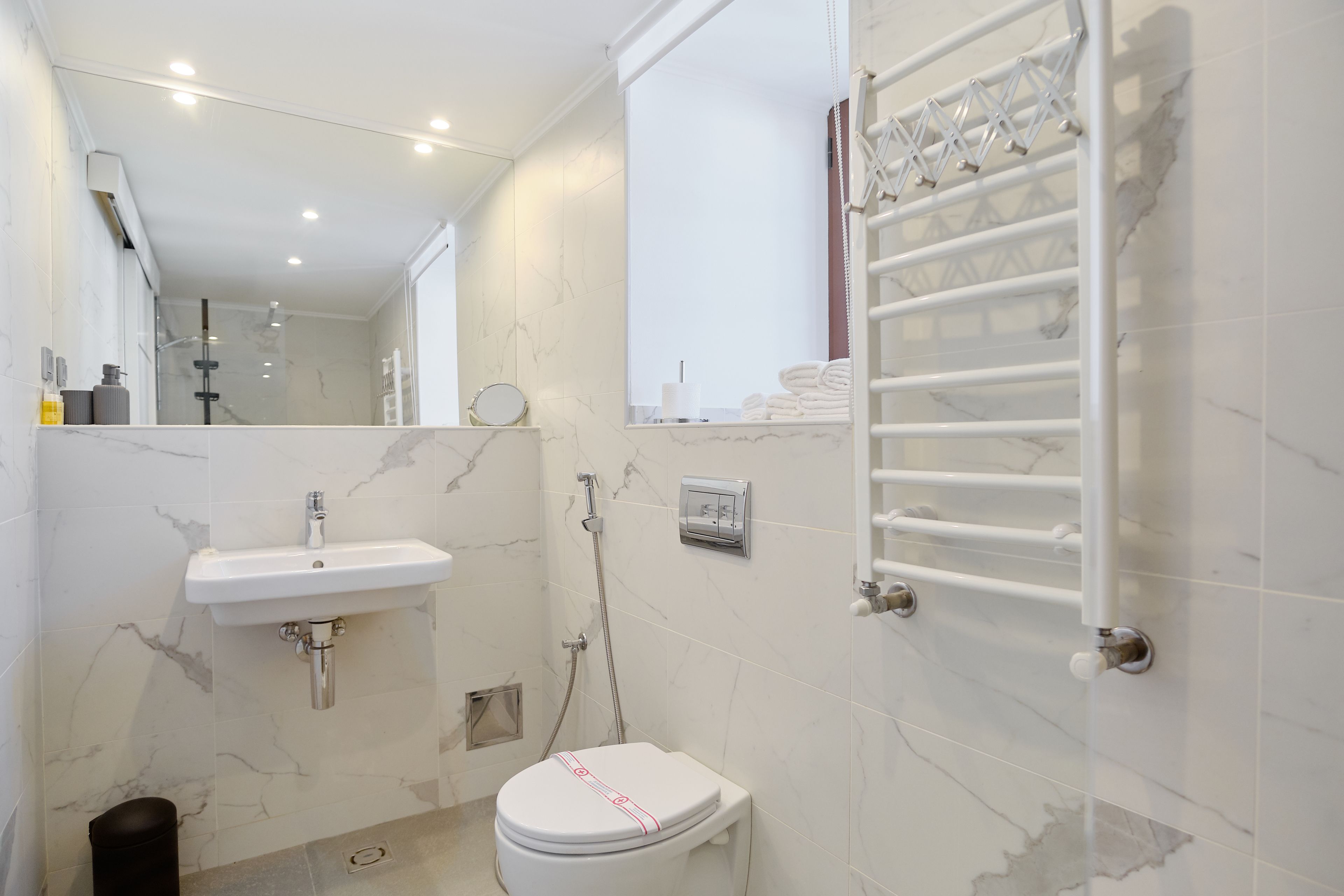 Un baño moderno con lavamanos, inodoro y ducha blancos.