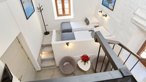 A modern interior with a staircase, a small seating area with cushions, a vase with flowers, and artwork on the walls. - Zebra  (Tivat)
