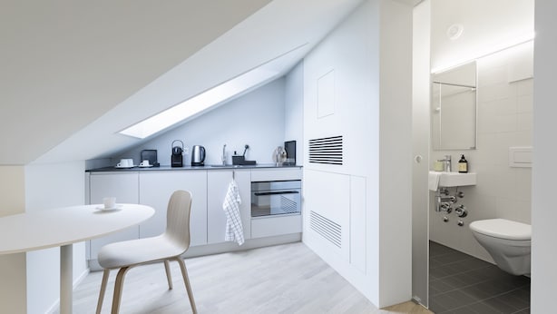 A modern kitchen with a dining area, a built-in oven, and a separate bathroom with a toilet and sink. - Dom Studios (St. Gallen)