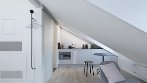 A modern kitchen with a dining area, including a small table and a chair, in a loft-style apartment. - Dom Studios (St. Gallen)