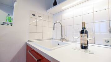 A kitchen with a white sink, stainless steel faucet, and a wine bottle on the counter.