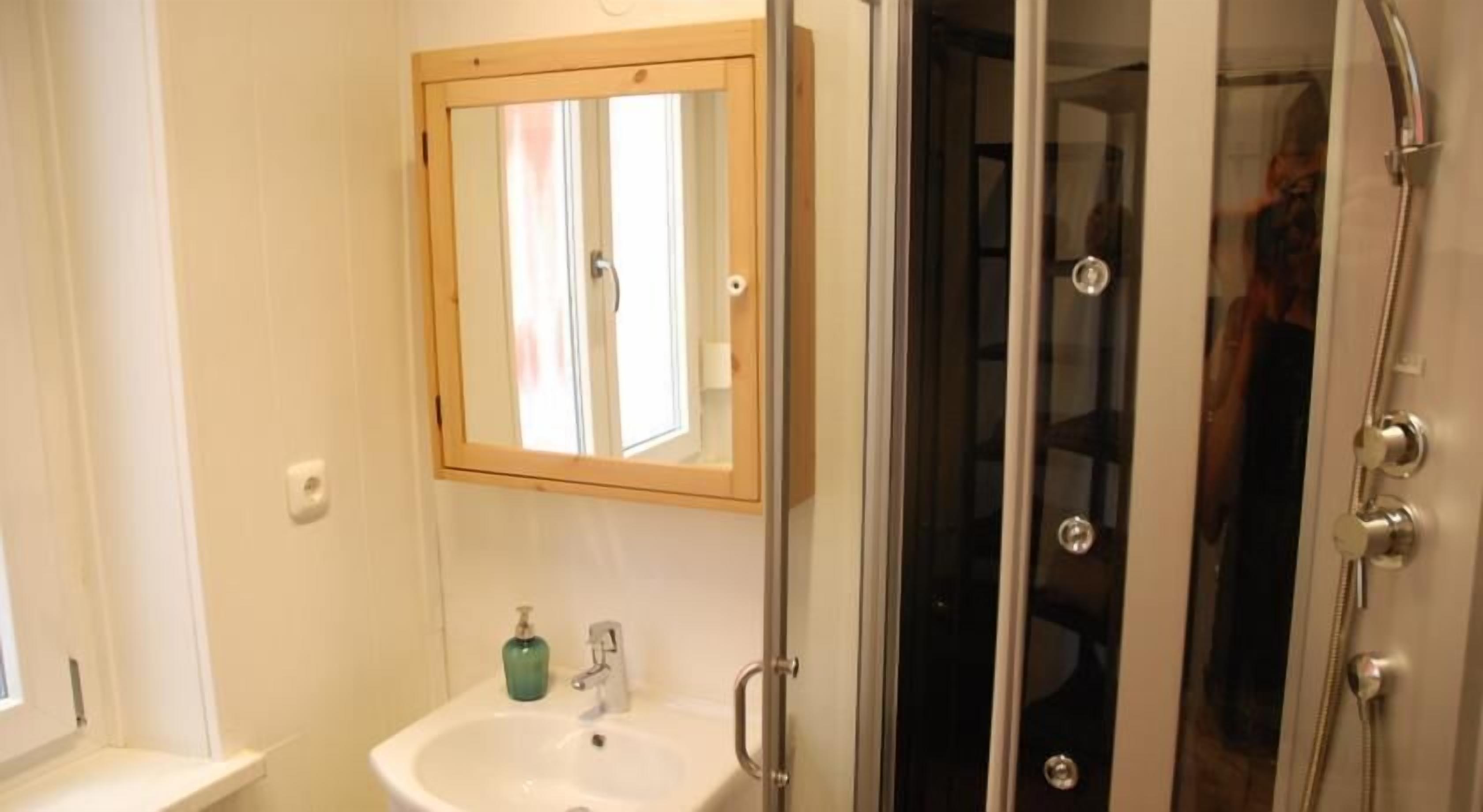 A bathroom with a sink, mirror, and shower.