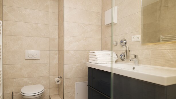 Un baño moderno con inodoro, ducha y tocador con espejo.