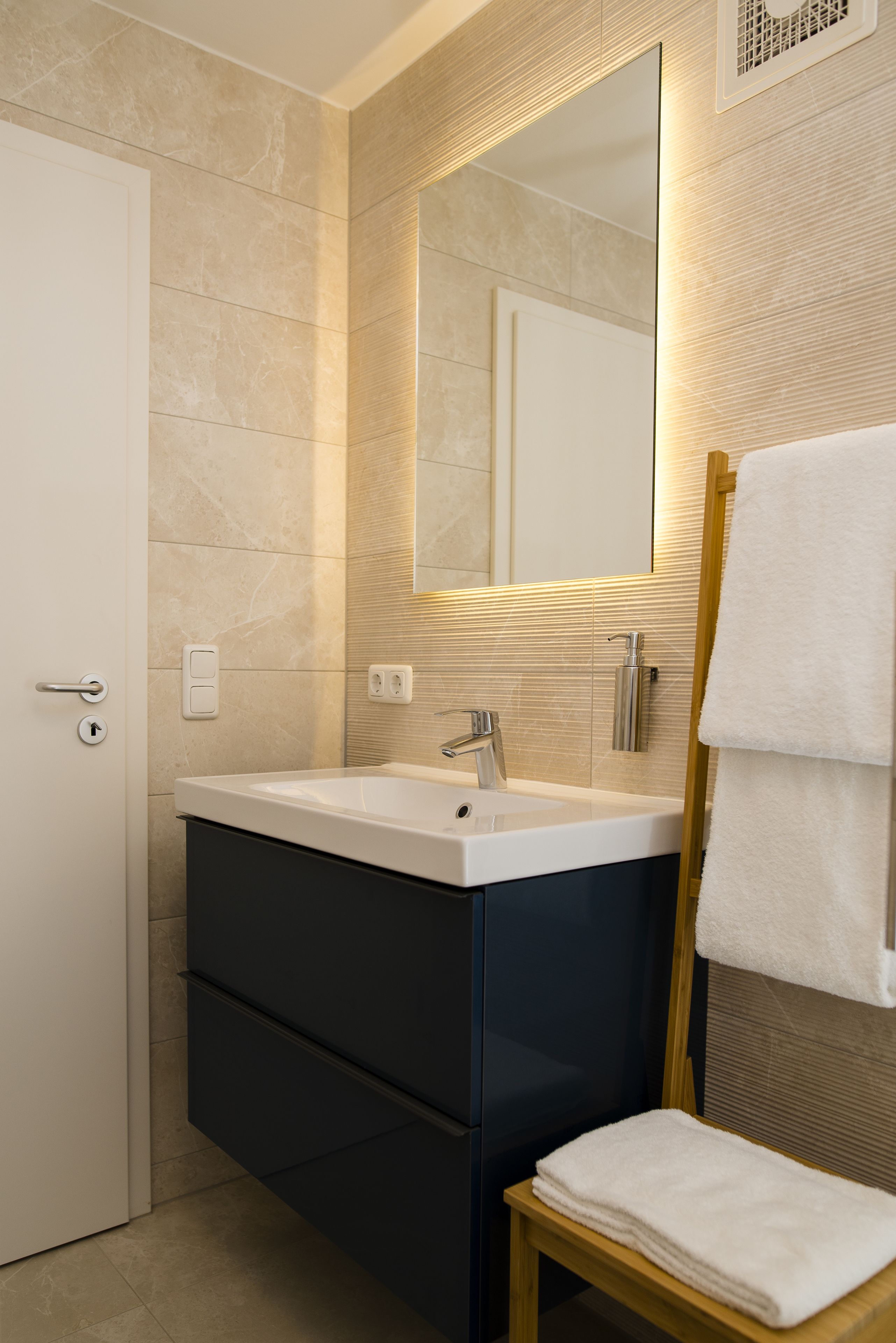 Un baño moderno con un espejo grande, un lavamanos y un perchero para toallas.