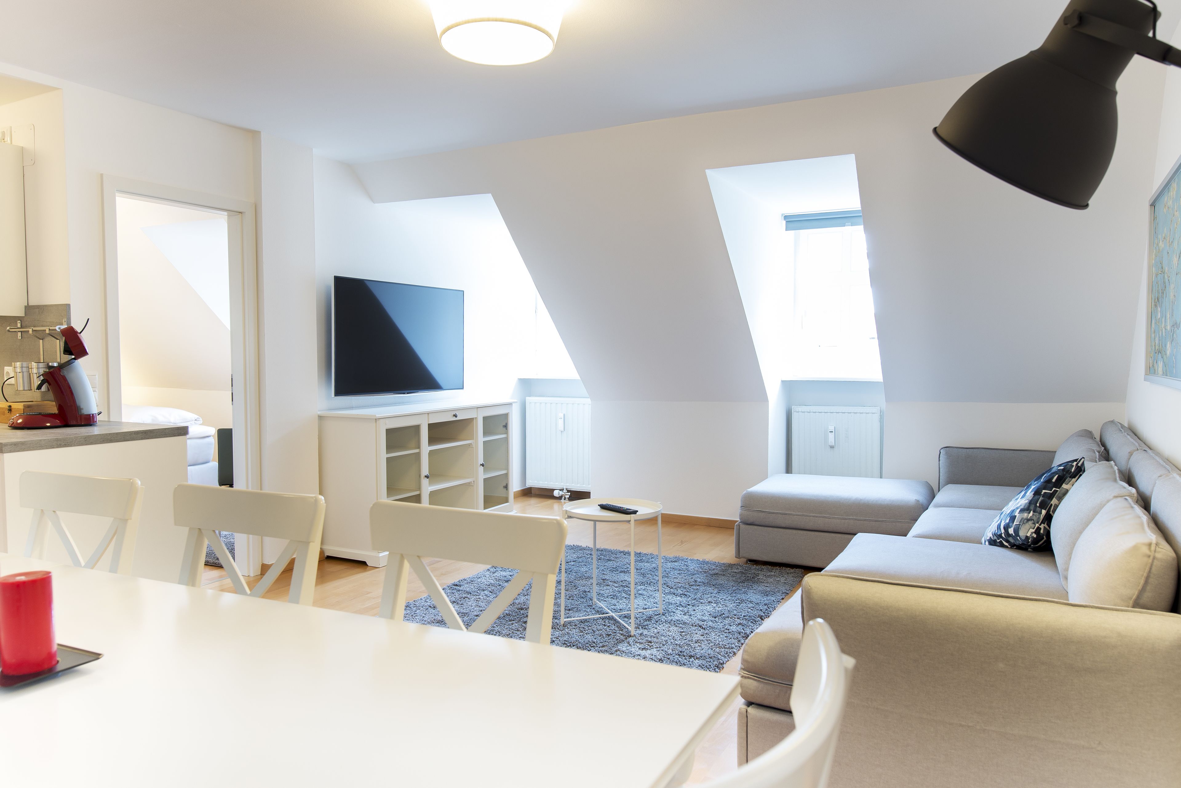 A modern living room with a sofa, a dining table, and a TV.