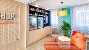 Een moderne kamer met een kitchenette, een zithoek met een gestreept tapijt, een stoel, een klein tafeltje en een hangplant.
