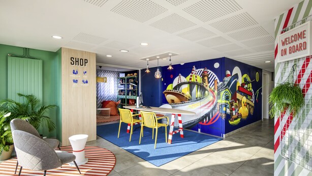 Een levendige kinderspeelruimte met een muurschildering, een winkeldeur en een uitnodigend bord met de tekst 'WELCOME ON BOARD'.