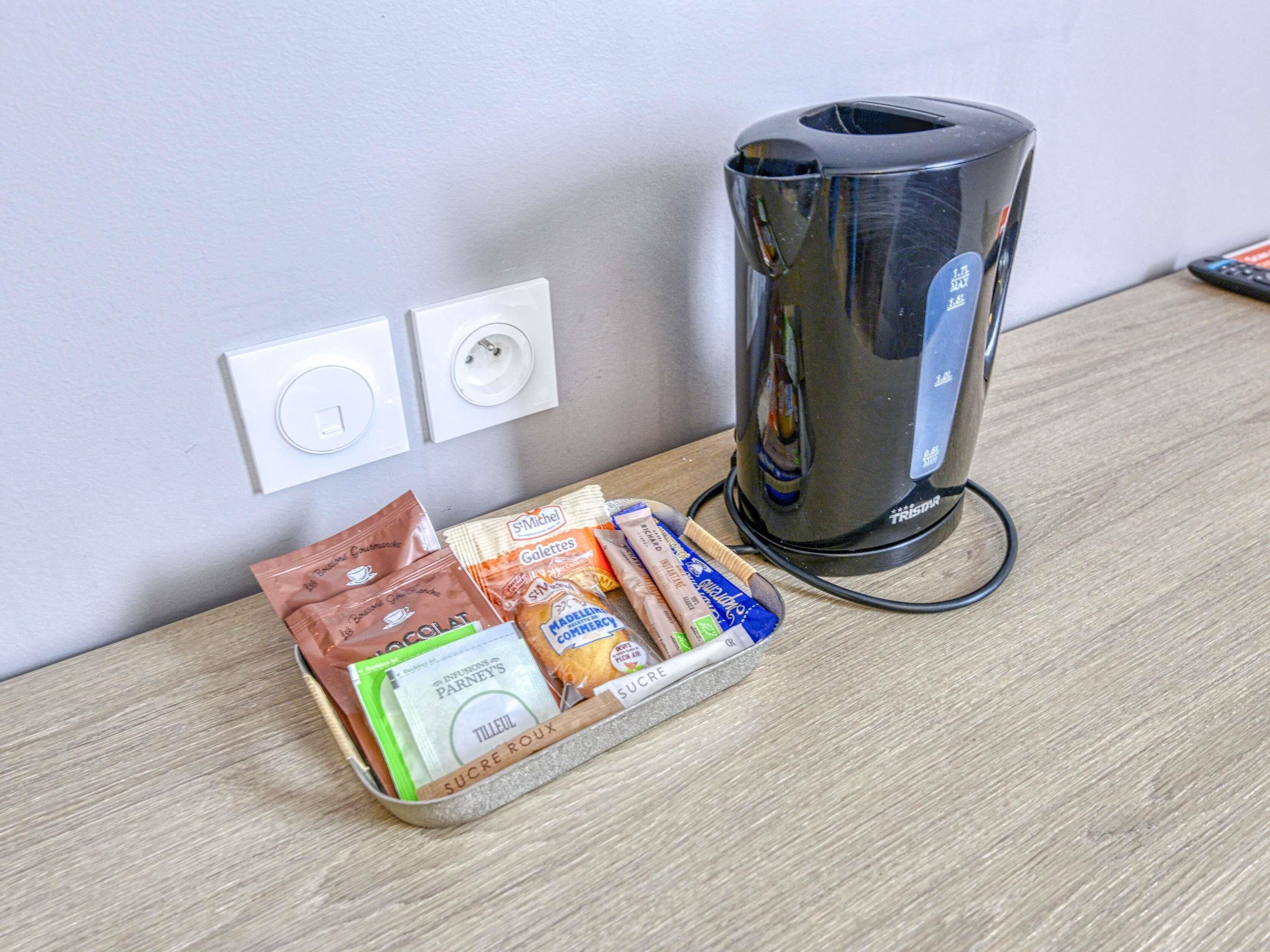 A coffee maker, a power outlet, and a tray with coffee pods and sugar packets.
