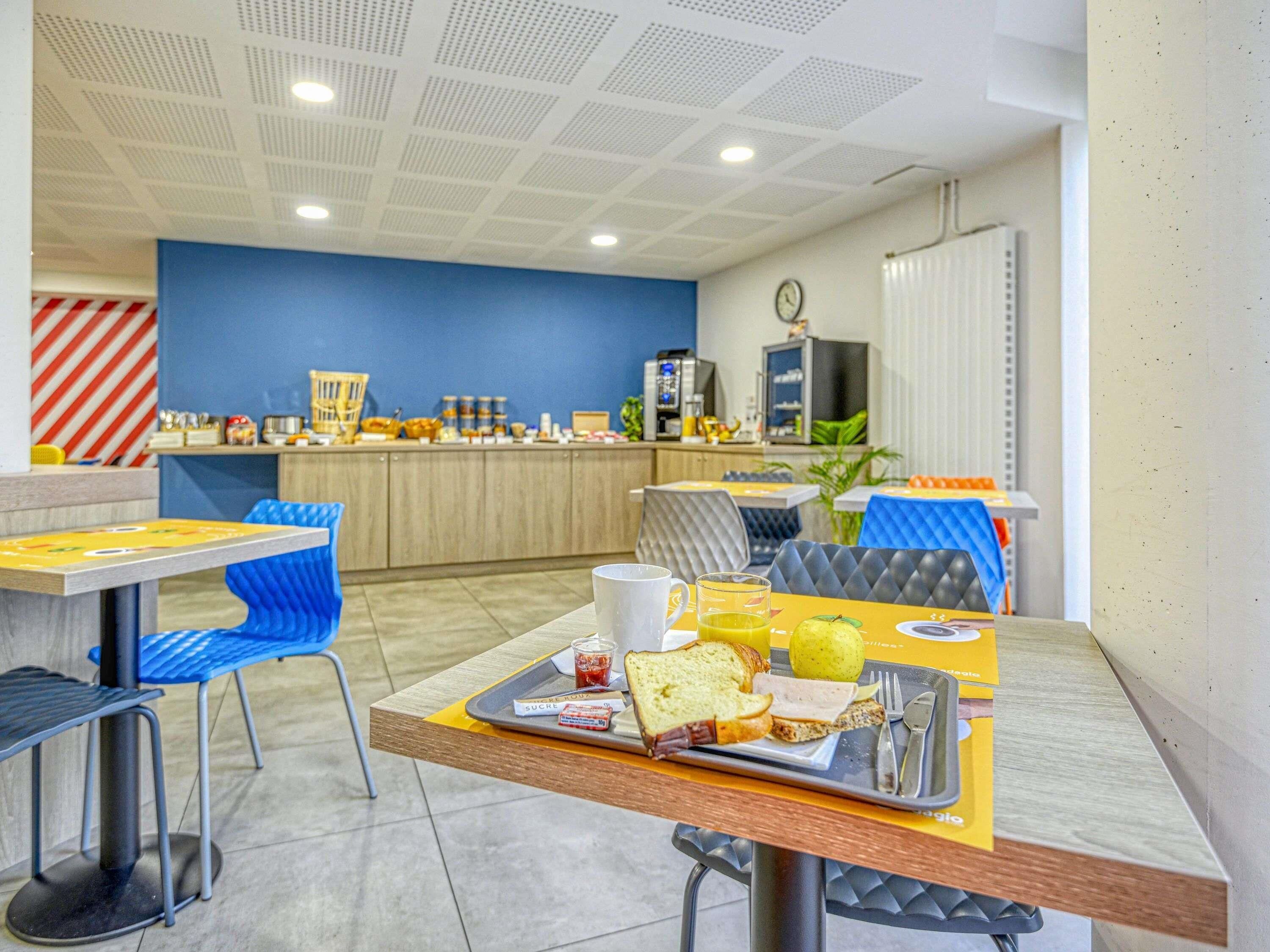 Zona pranzo con tavoli e sedie, un banco buffet e un orologio appeso al muro.