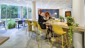 Een binnengedeelte met een modern plafond, een toonbank met stoelen, en uitzicht op groen buiten.