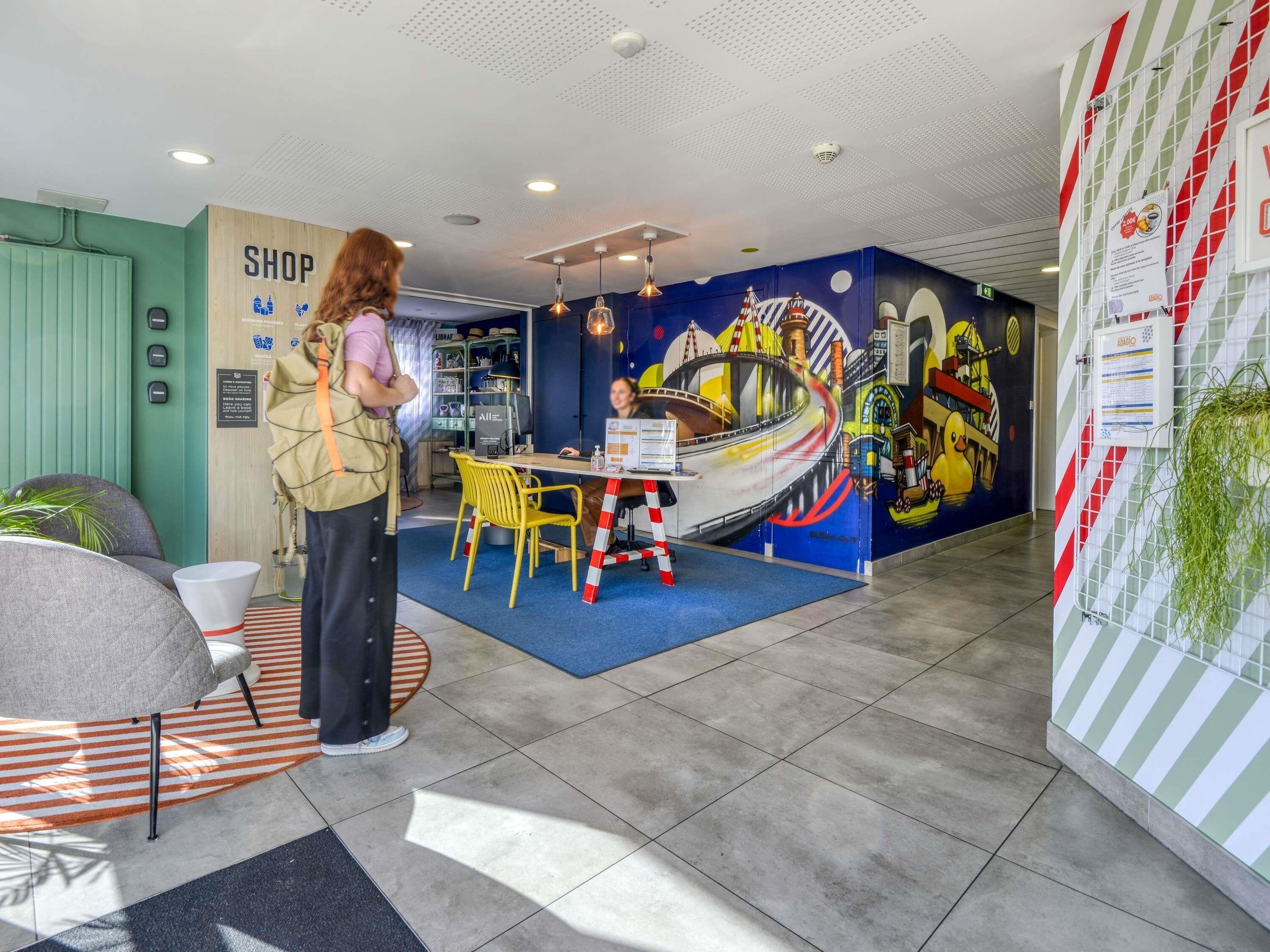 A reception area with a desk, chairs, a mural, and a sign that reads 'SHOP.'