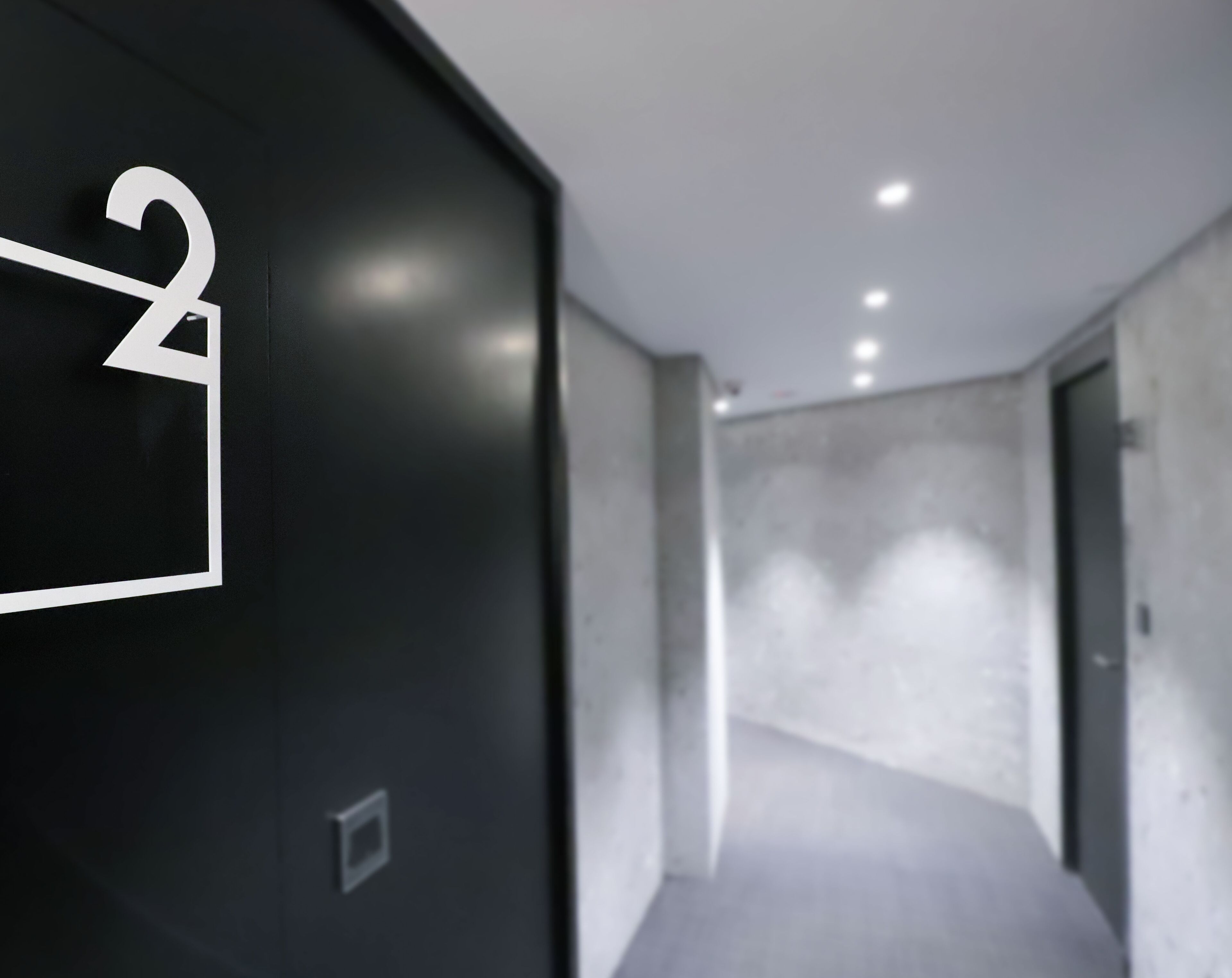 A modern hallway with a black wall featuring a white number '2' sign.
