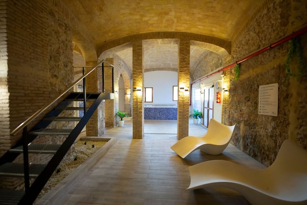 A spacious lobby with a modern staircase, seating areas, and a view of a pool. - Hotel Xauen (Montanejos)