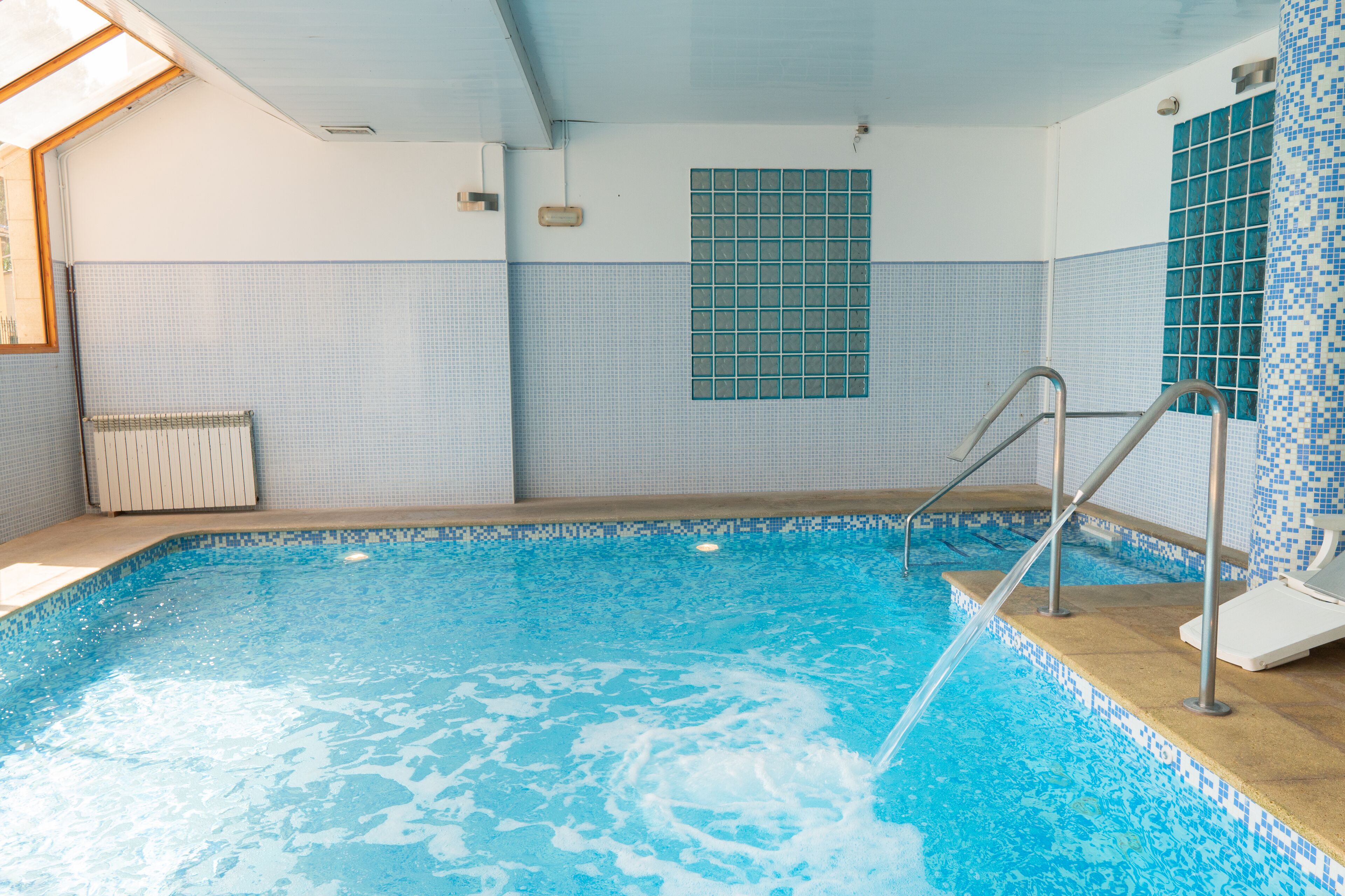 A swimming pool with a tiled wall, a window, and a radiator.