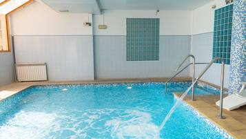 A swimming pool with a tiled wall, a window, and a radiator.