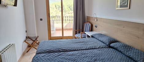 A bedroom with a large bed, a chair, a small table, and a view of a balcony with a railing.