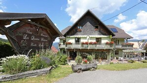 A traditional chalet-style hotel with a balcony, a wooden signboard, and a garden area. - Hotel Les 4 Saisons (Kruth)