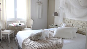 A hotel room with a bed, two chairs, a small table, a lamp, and a window with curtains. - Hotel Les 4 Saisons (Kruth)