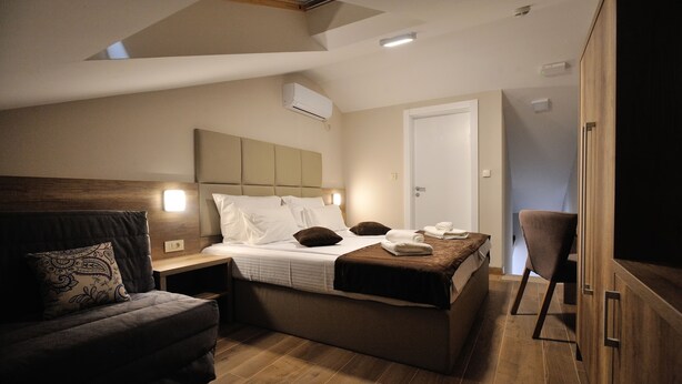 Um quarto moderno com uma cama, um sofá, uma poltrona e um guarda-roupa.