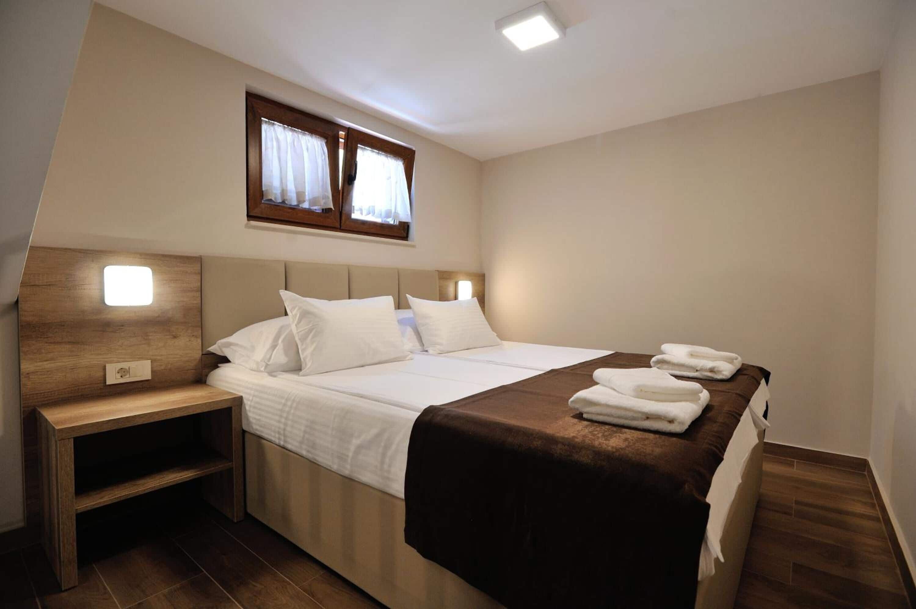 A neatly made bed with white linens, a wooden headboard, and a bedside table with a lamp.