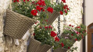 Wicker baskets with red flowers hanging on a stone wall.