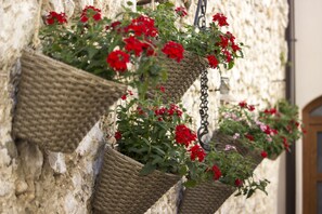 Wicker baskets with red flowers hanging on a stone wall.