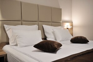 A neatly made bed with white and brown pillows, a headboard, and a bedside lamp.