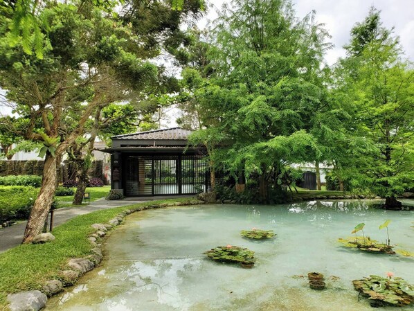 A traditional Japanese-style pavilion with a tiled roof, surrounded by lush greenery and a small pond with lily pads. - Gaeavilla Resort (Ji'an)