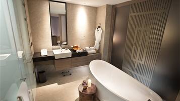 Un baño moderno con cabina de ducha de vidrio, una bañera independiente, un lavamanos con espejo y un perchero para toallas.