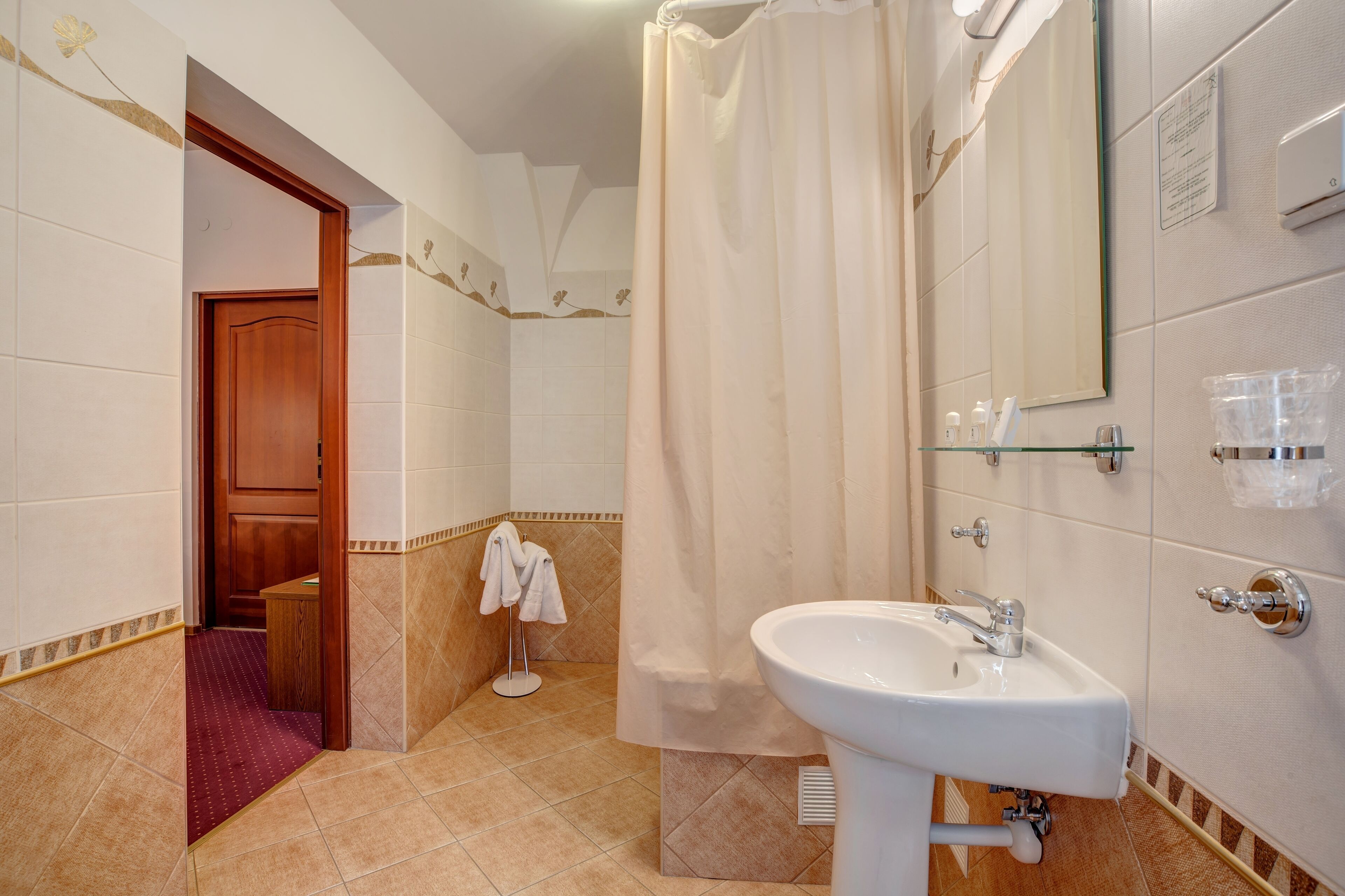 A bathroom with a shower curtain, a sink, and a mirror.