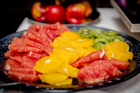 A plate of sliced fruits including grapefruit and mango.
