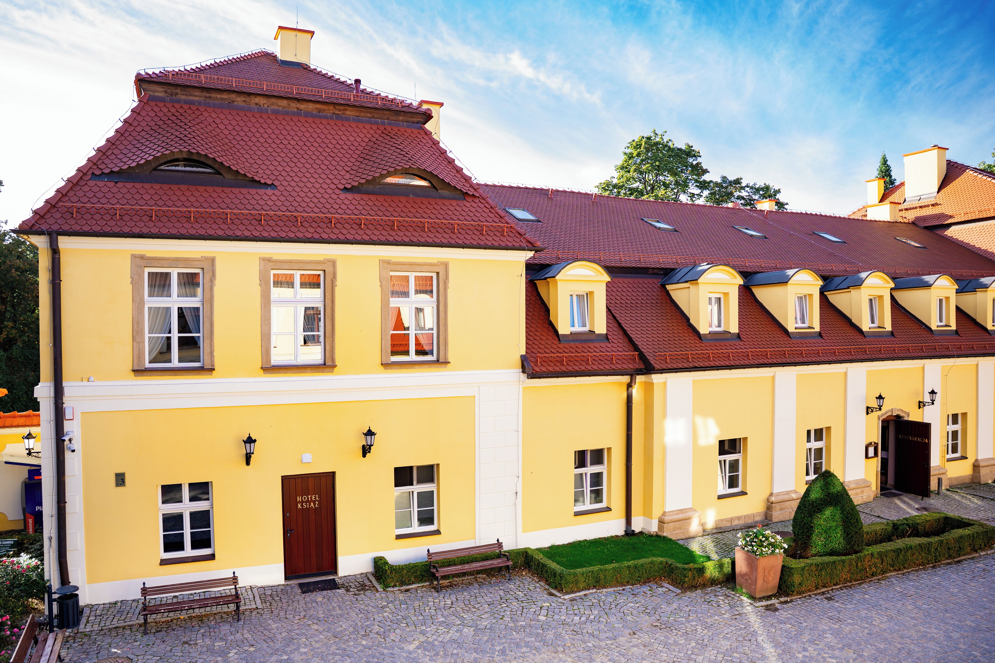 A yellow building with a red roof, multiple windows, and a door labeled "HOTEL."