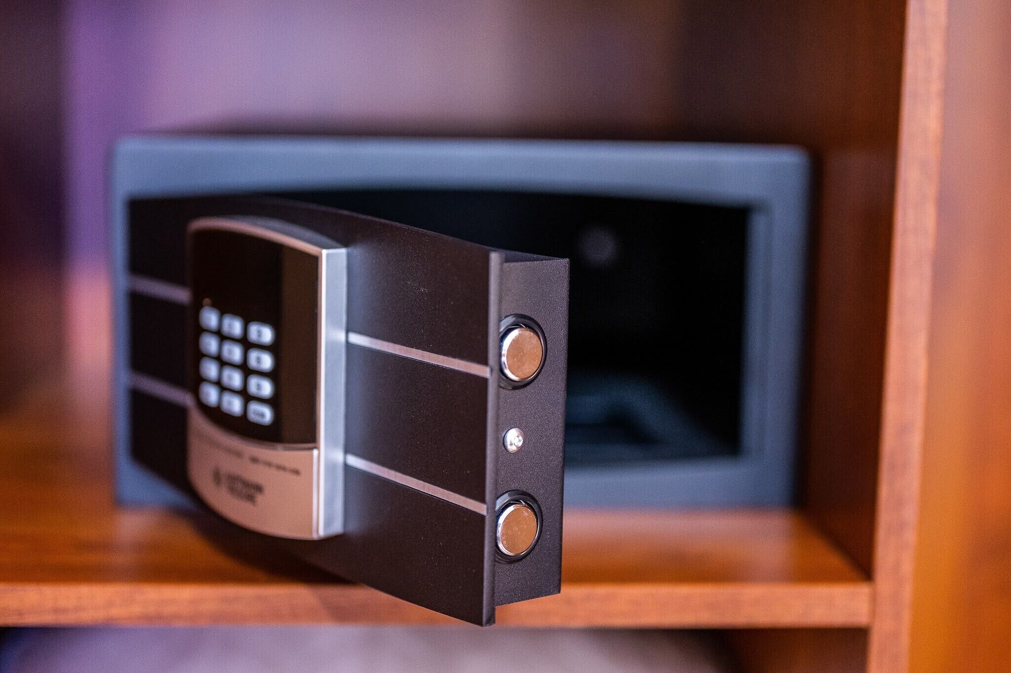 A black electronic device with a keypad and three circular buttons on a shelf.