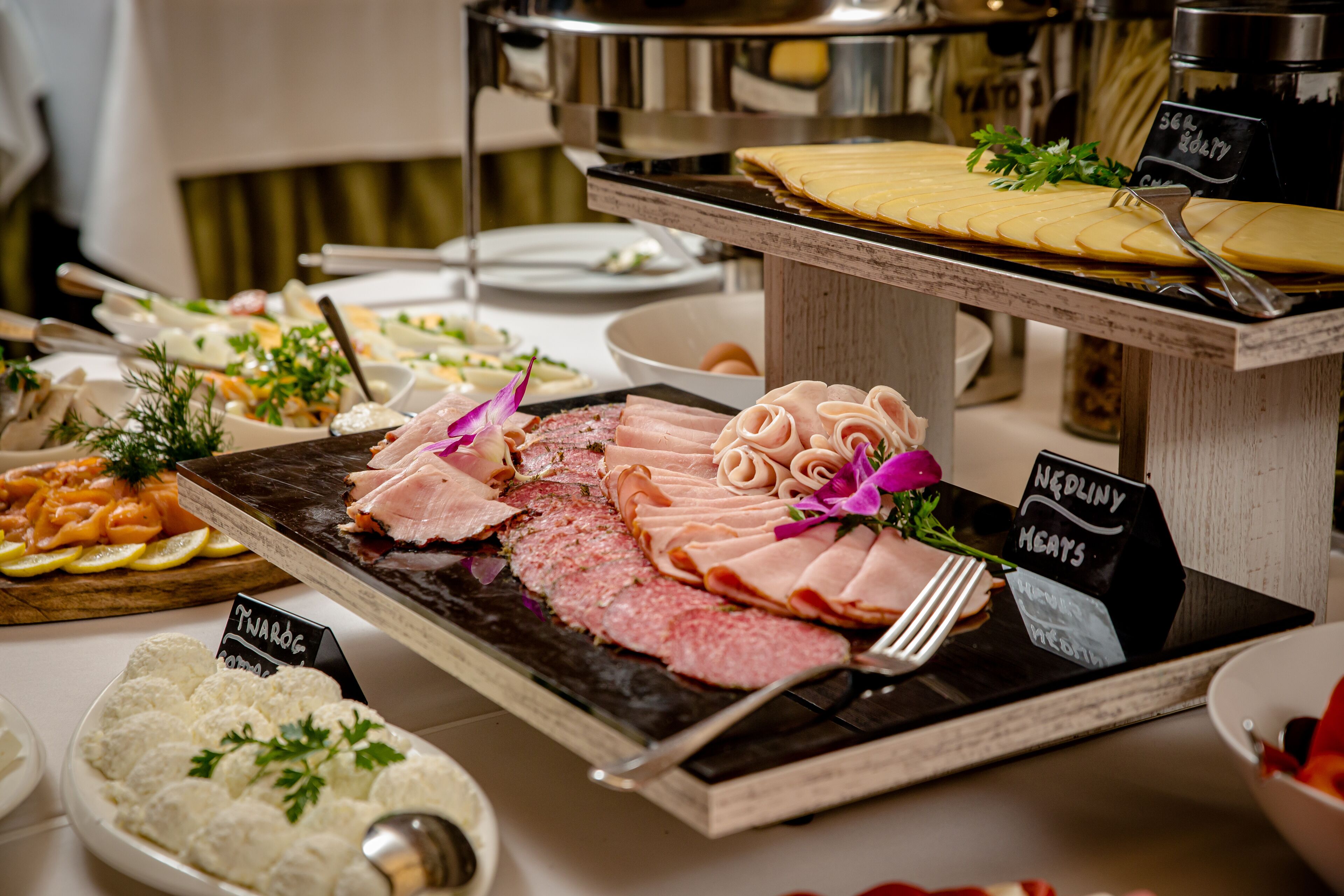 A buffet with various food items including meats, cheeses, and garnishes.