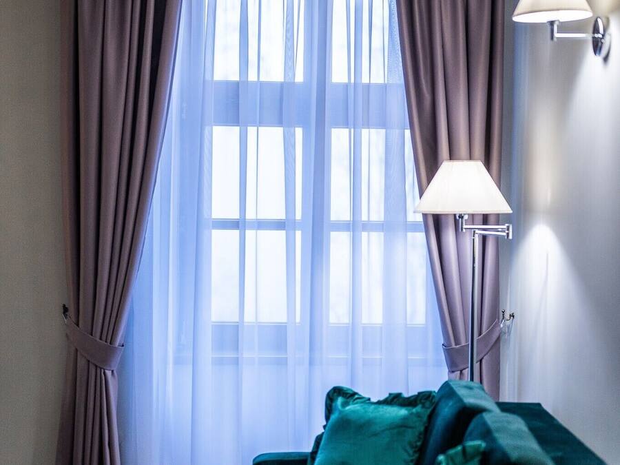 Una habitación con un sofá verde, una mesa de madera y una ventana con cortinas.