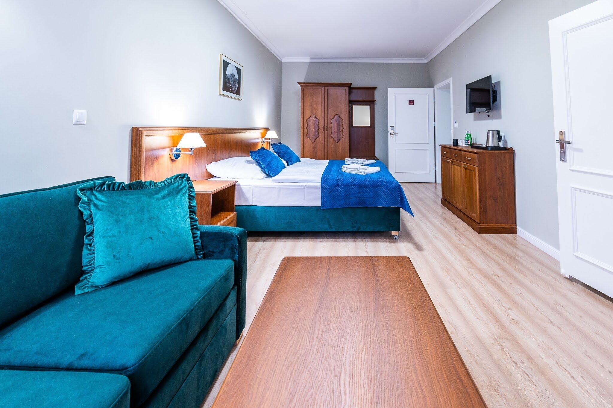 Ein Hotelzimmer mit einem Bett, einer Couch, einem Holzschrank und einem Fernseher.