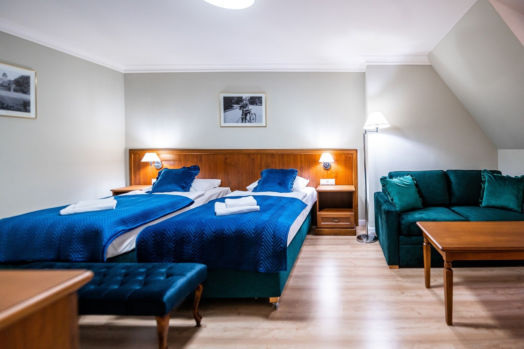 Habitación de hotel con dos camas, un sofá, una mesa y una lámpara.