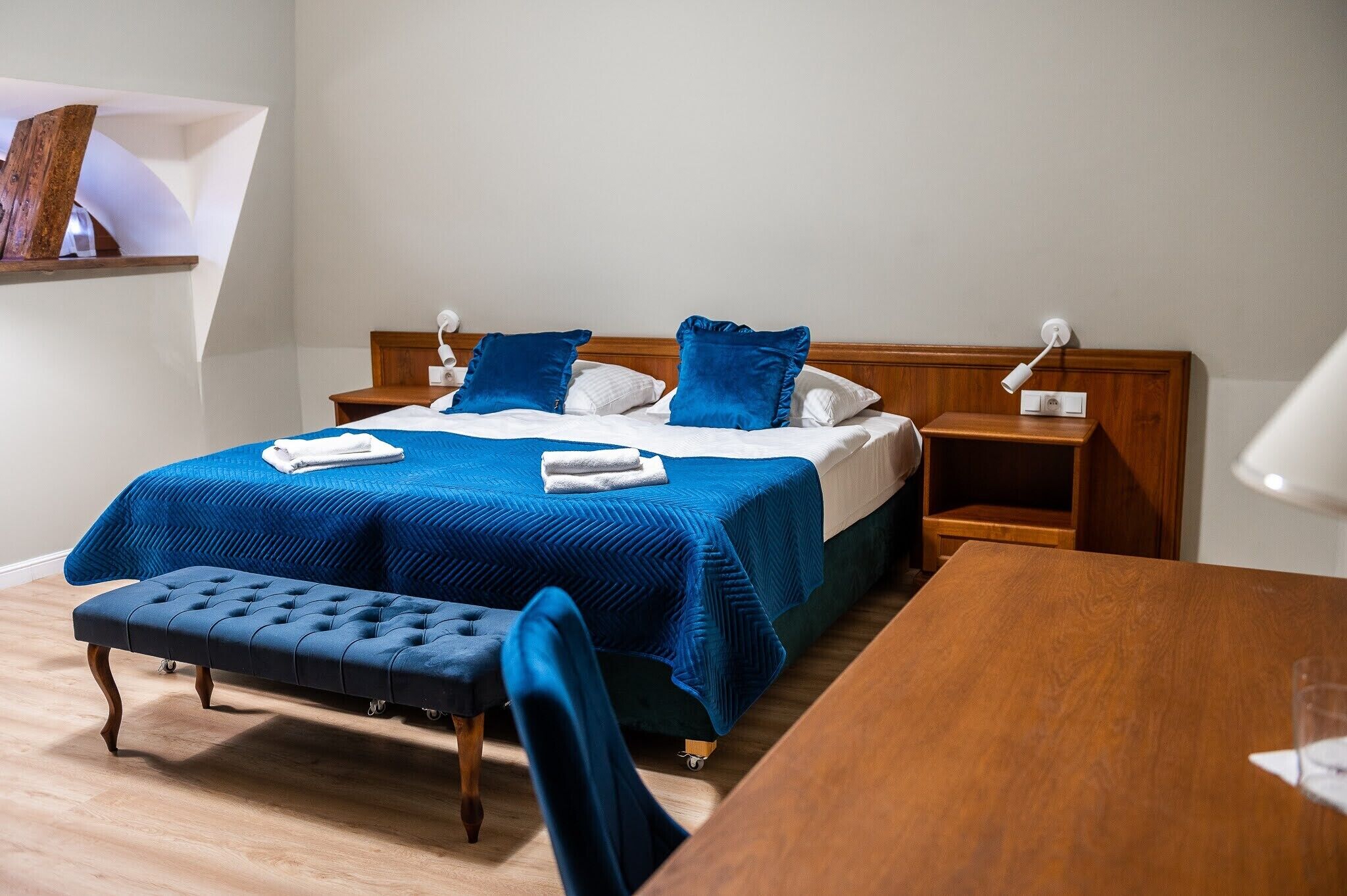 A neatly arranged hotel room with a bed, bedside table, and a small desk.