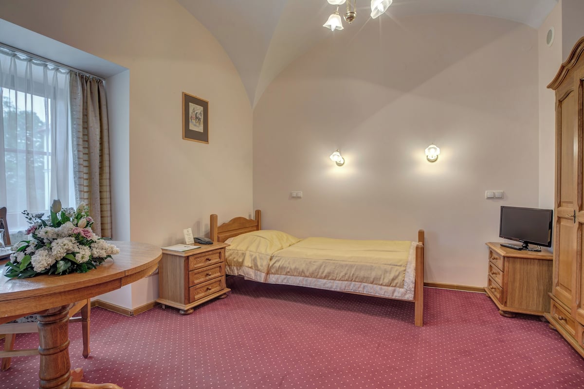 Ein Schlafzimmer mit Bett, Nachttisch, Holzschrank und Fernseher.