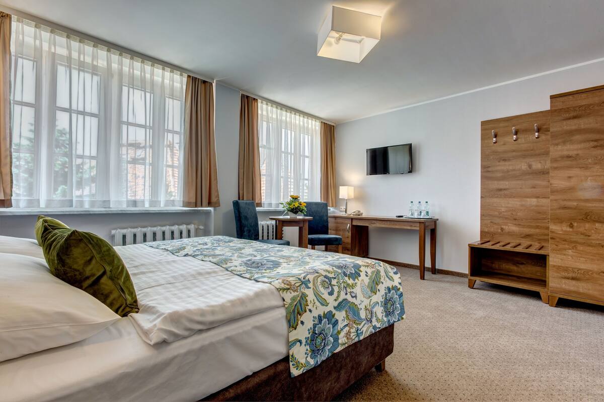 Ein Hotelzimmer mit einem Bett, einem Schreibtisch, einem Sessel, einem Fernseher und einem Kleiderschrank.